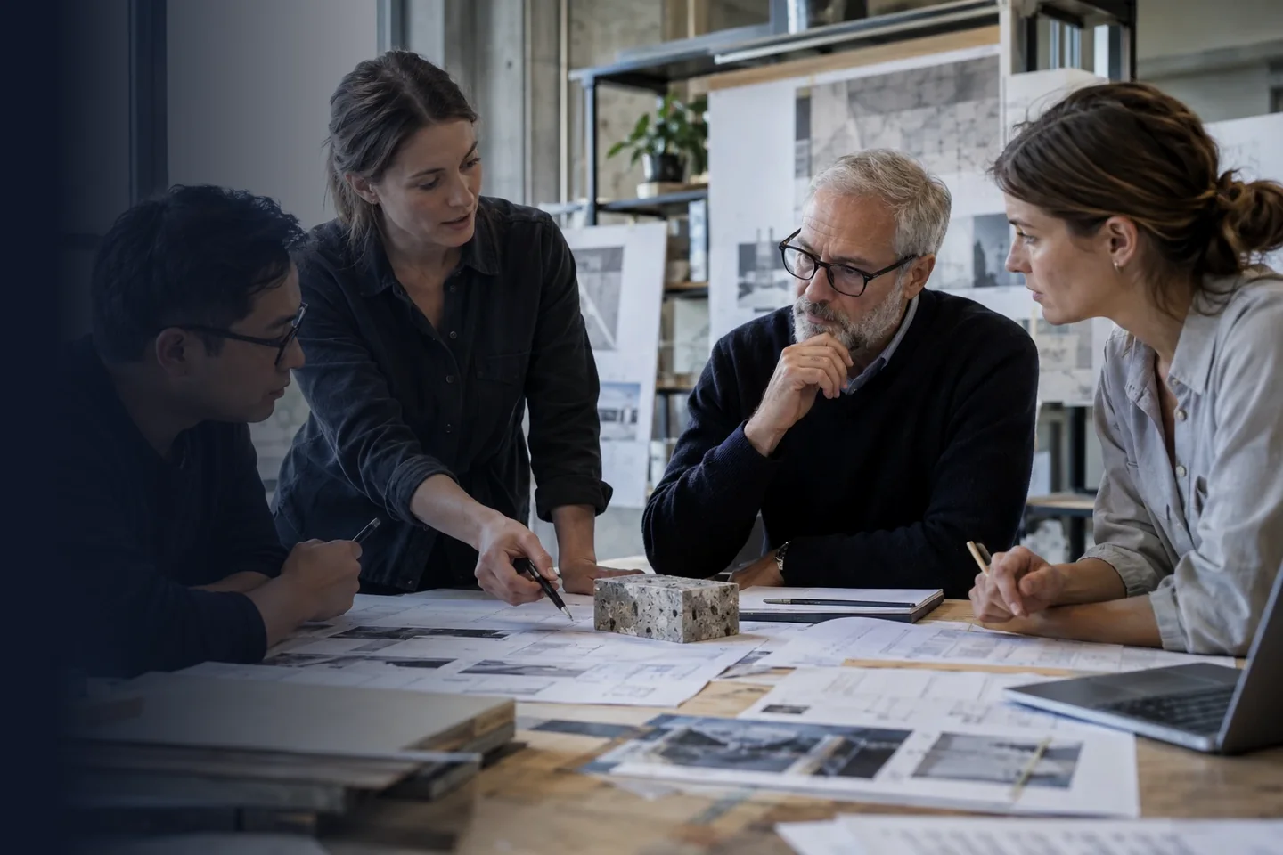 Equipo de profesionales revisando planos y muestras de material en una mesa de trabajo.