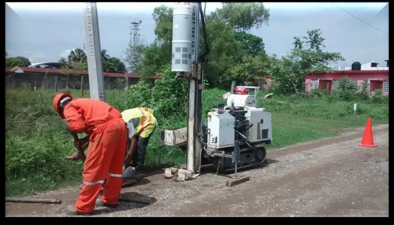 Brigada de campo operando una perforadora de exploración geotécnica sobre un camino rural